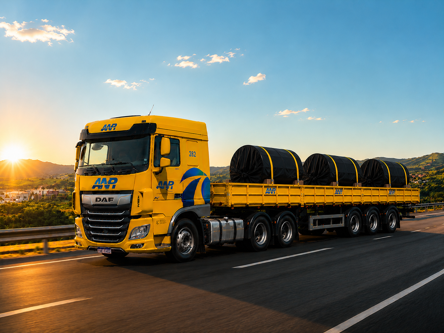 Caminhão DAF A.N.R amarelo transportando bobinas de aço em rodovia ao entardecer